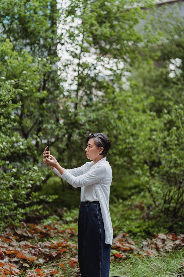 A woman poses to take a video of something in front of her.
