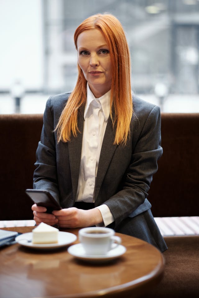 A woman in a business suit uses her cell phone.
