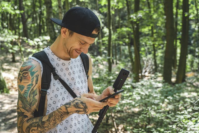 A man smiles as he looks at his smartphone.
