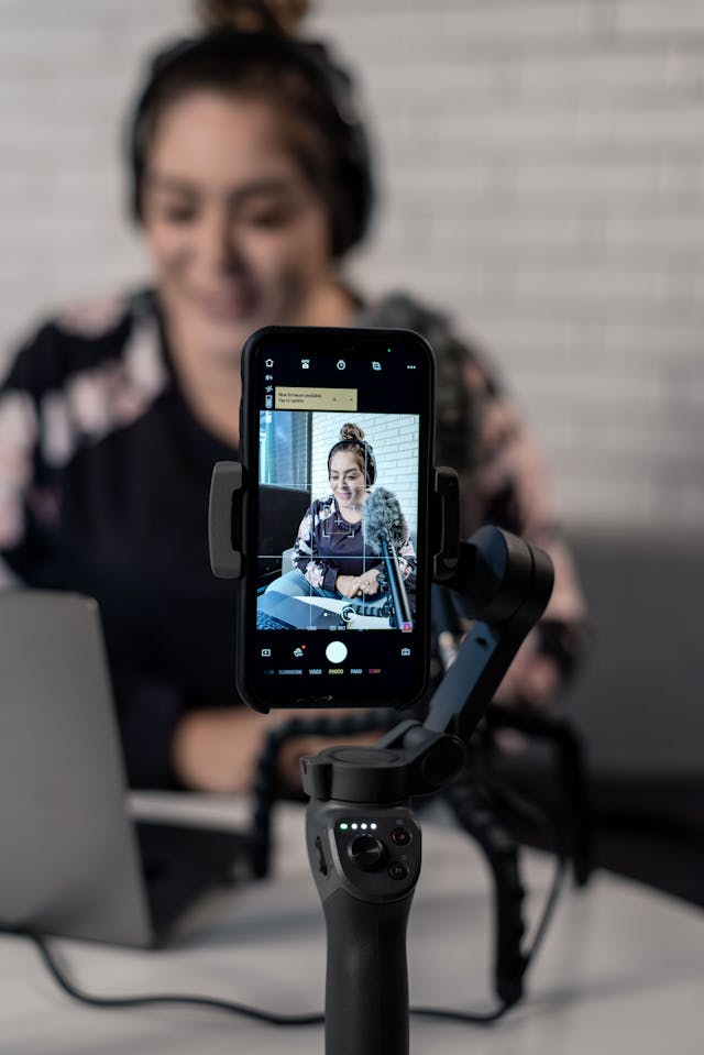 A woman records herself speaking into a microphone.
