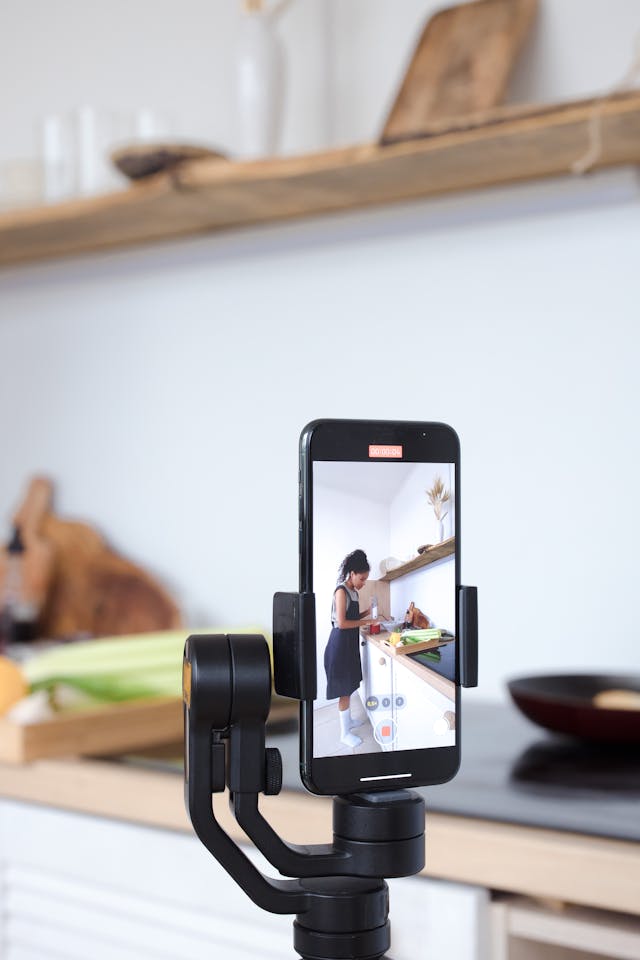 A phone camera records a woman preparing a meal.
