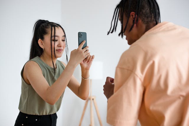 A woman takes a video recording of a man.
