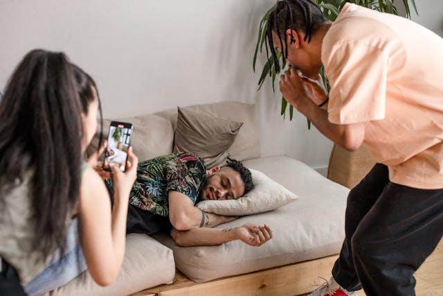 Duas pessoas gravam um homem enquanto ele dorme.
