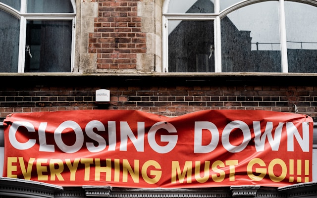 A big banner on the side of an old brick building says, “Closing down, everything must go.”
