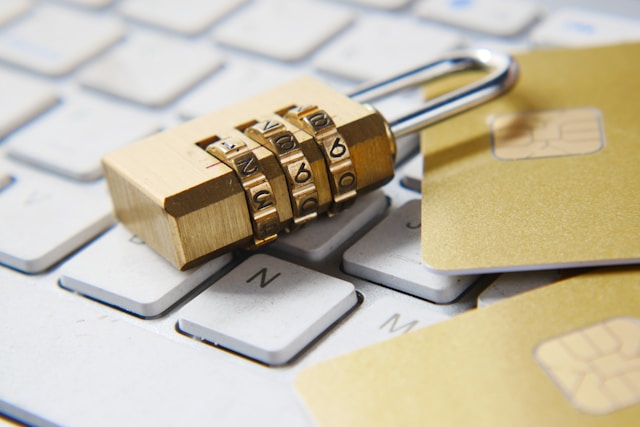 A combination lock sits beside two SIM cards on top of a laptop keyboard. 
