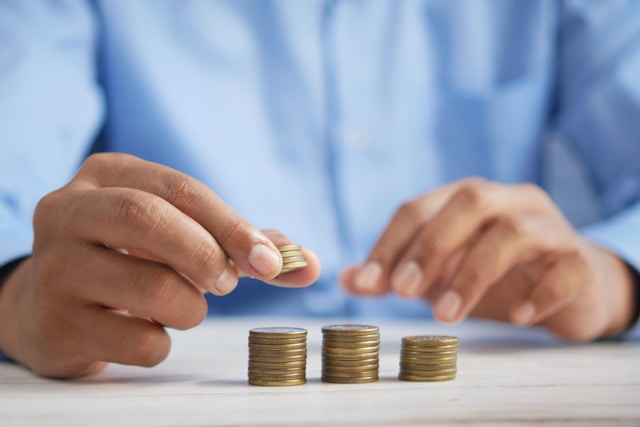 A person stacks coins on a table. 
