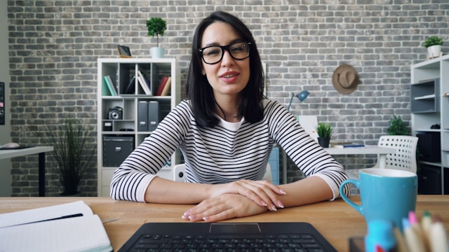 A woman sits in front of a laptop while she speaks to her audience in a TikTok video. 
