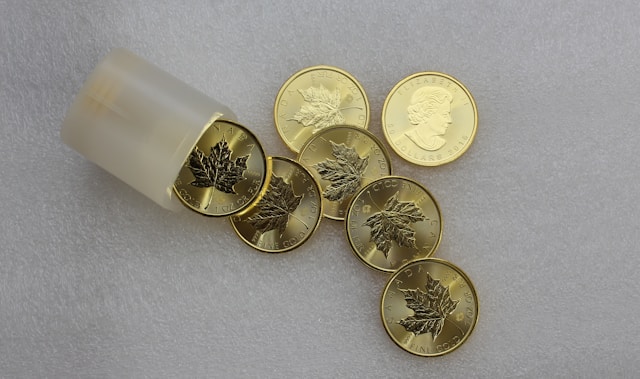 Seven small gold coins are scattered on a table. 
