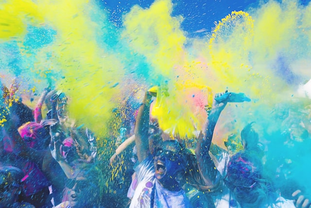 A big crowd cheers as colored powder explodes over them. 
