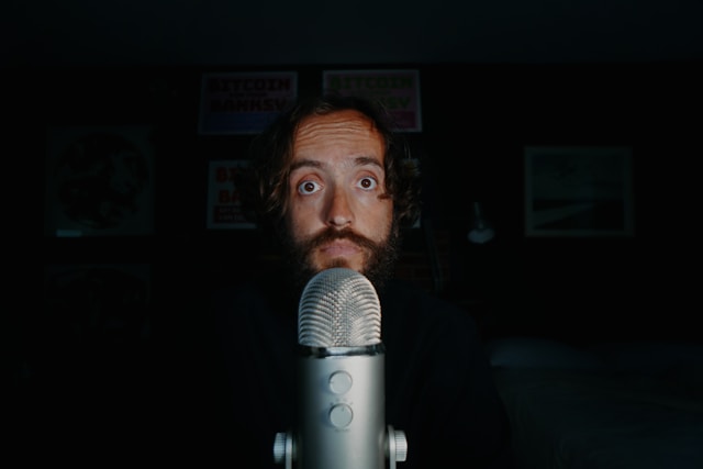 A creator sits in front of a microphone for his YouTube or TikTok video. 
