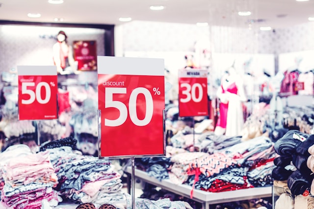 Various apparel products are displayed on tables together with different discount signs. 
