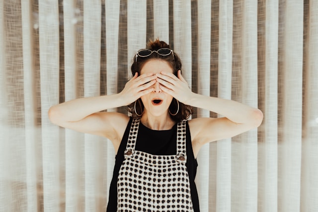 A woman covers her eyes with her hands. 
