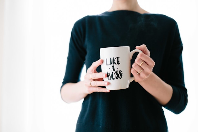 A woman holds a mug with the words “Like a boss” printed on it. 
