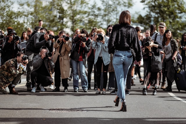 A big group of paparazzi takes pictures of a female celebrity. 
