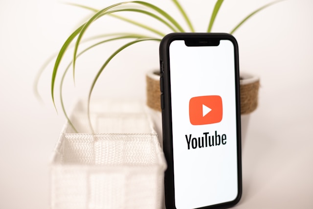 A phone screen displays the YouTube logo and name as the app loads. 
