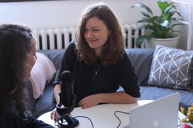 Two women sit in front of a microphone and a laptop for a TikTok LIVE.