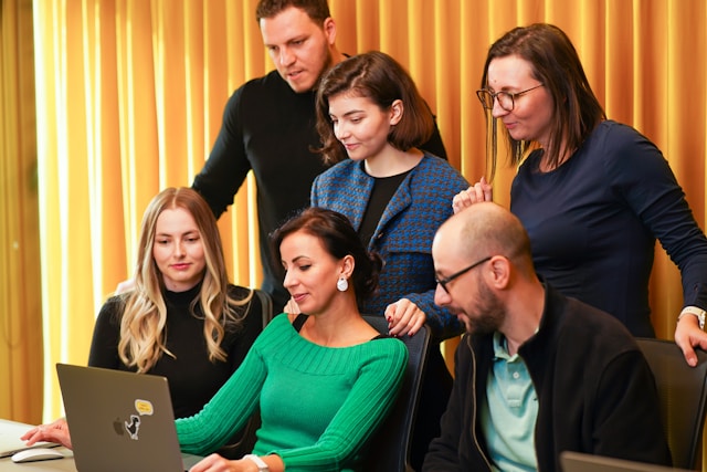 A group of ad creatives gather around a laptop to discuss their TikTok marketing strategy. 
