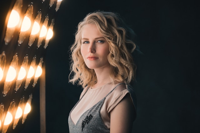 A female celebrity stands in front of rows of spotlights. 
