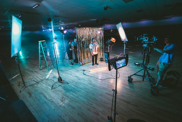 A man stands in front of a shiny curtain as several cameras film him.