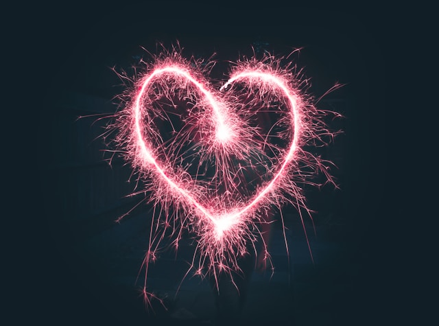 A red sparkler forms the shape of a heart. 
