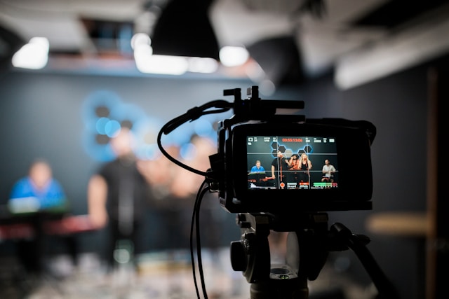 A video camera is set up to record a band’s performance in a studio. 
