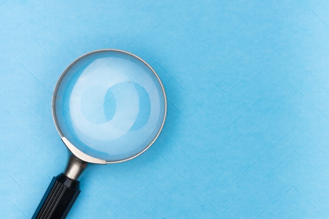 A magnifying glass sits on top of a blue table. 
