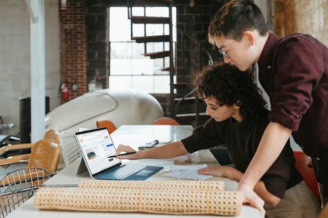 Two business partners study sales numbers on a laptop.
