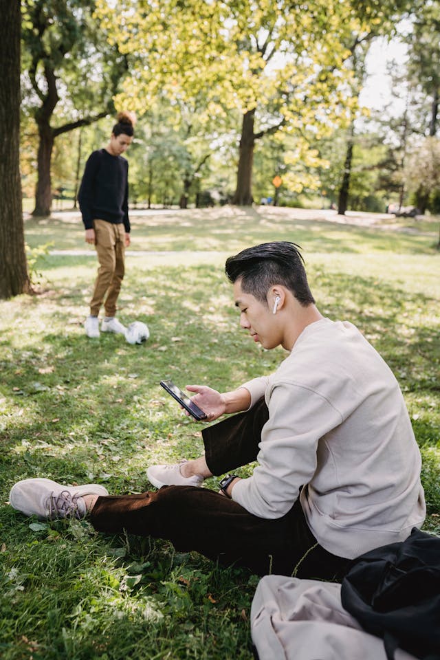 A man in a park uses his cell phone.
