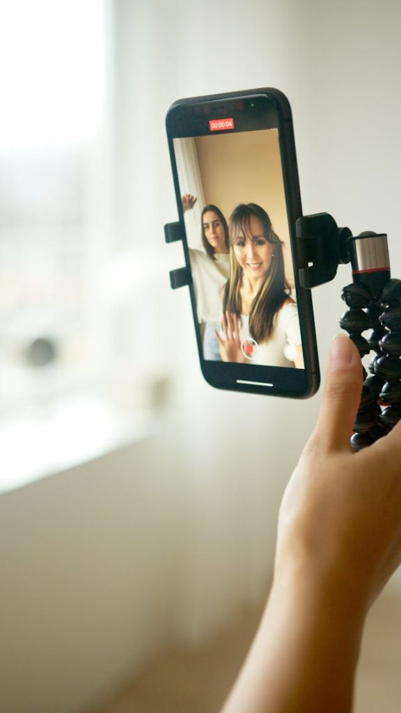 A woman holds a camera to record herself and another woman.
