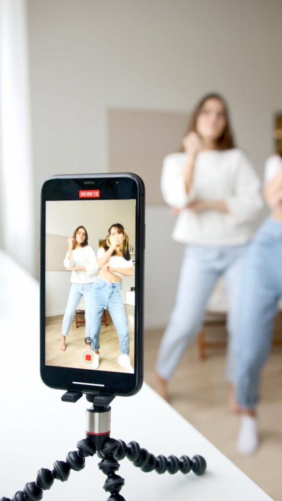 Two women record themselves dancing.
