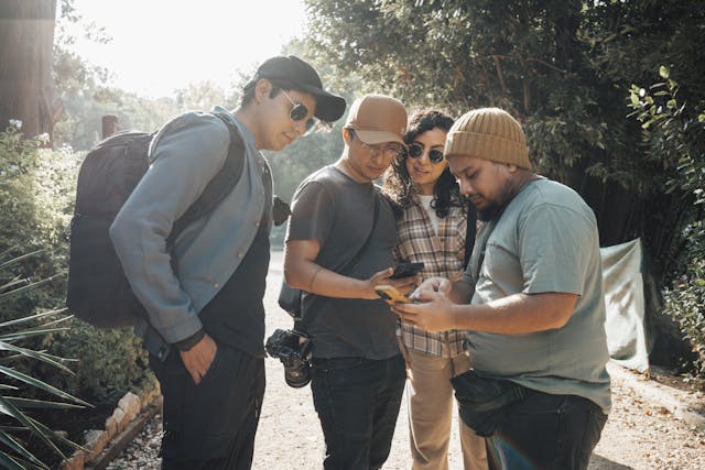 A group of four people stare at the content on their phones.
