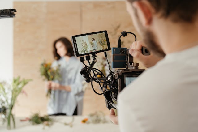 A man records a woman using a large professional camera.