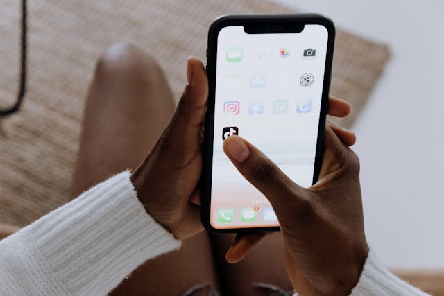 A person taps on the TikTok app on their home screen.
