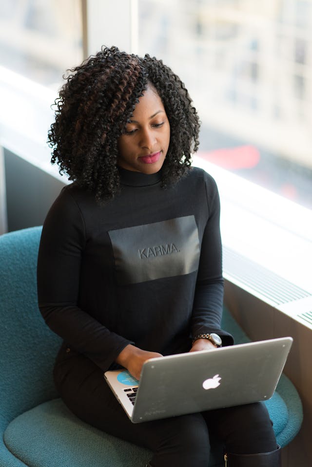 A woman types on the laptop on her lap.
