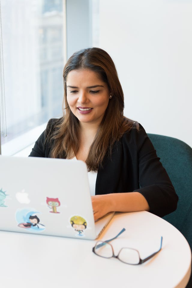 A businesswoman smiles as she types on her laptop.
