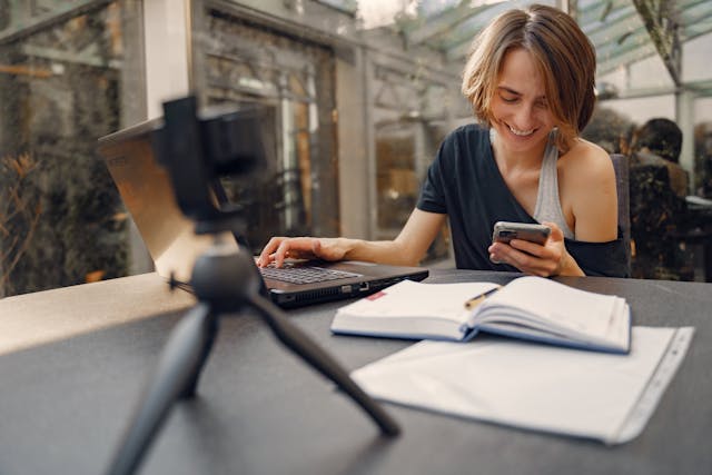 A woman grins as she looks down at her phone.
