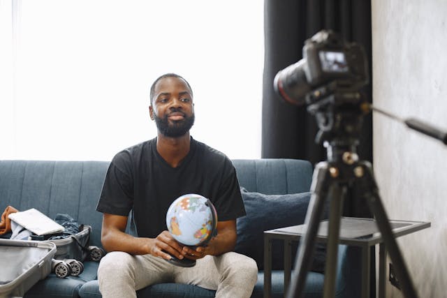 A man looks into a professional camera and smiles.
