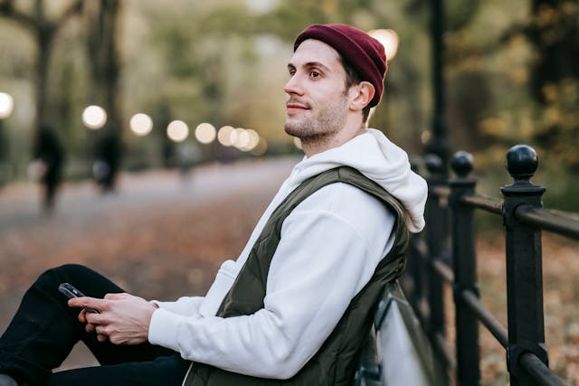 A man on a park bench looks up from his phone.