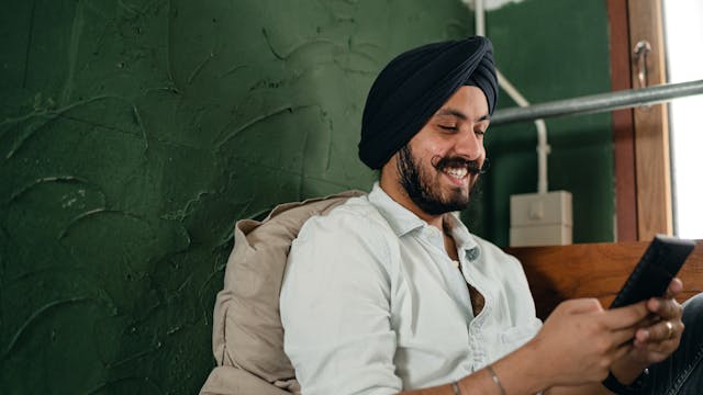 A man scrolls on his phone happily.
