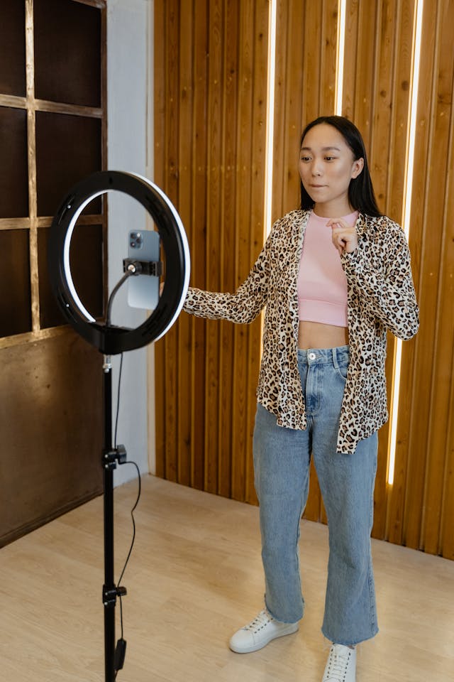 A woman in a leopard print sweater stands before a mounted cell phone.