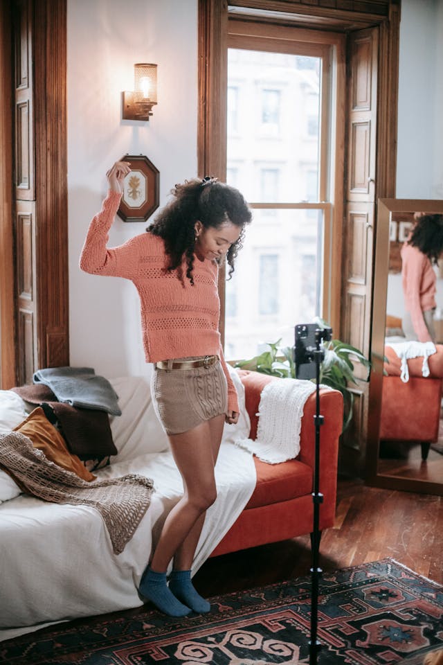 A phone on a tripod records a woman showing off clothes.
