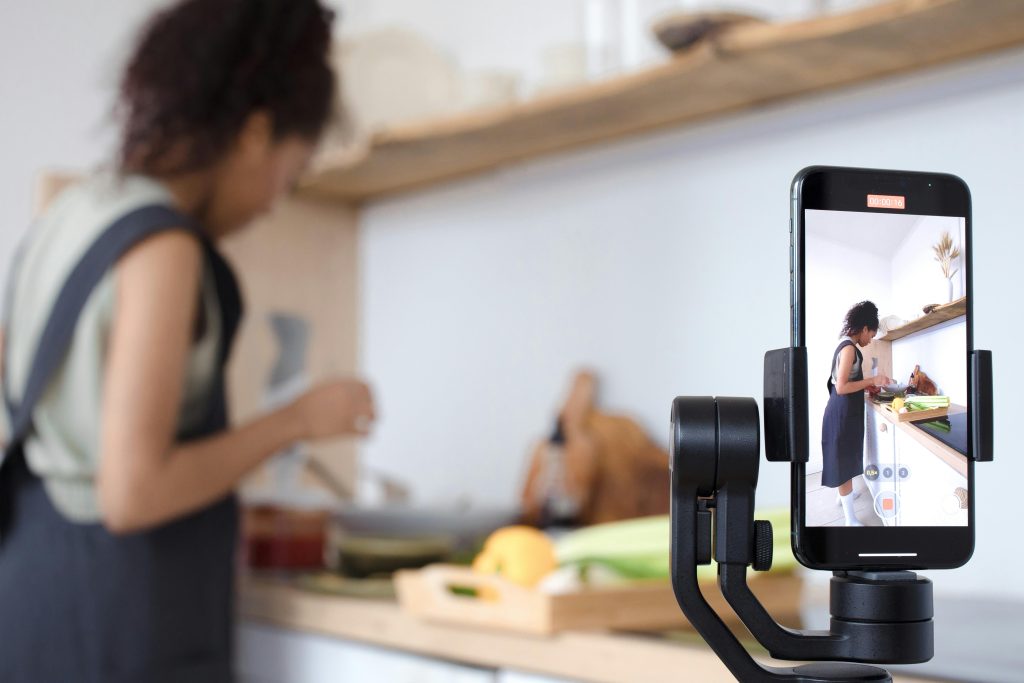 A person records themself with an iPhone cooking in a kitchen.
