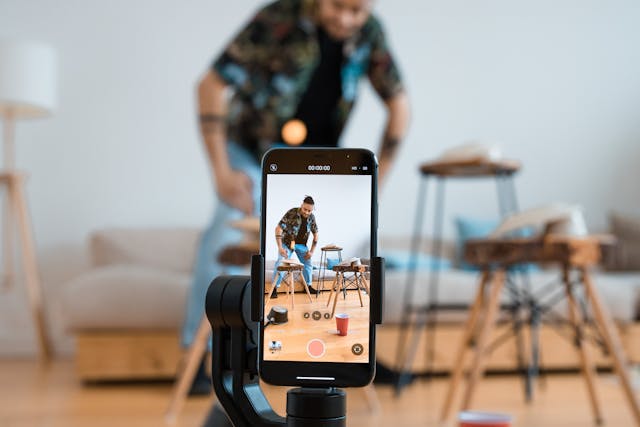 A man records himself with his phone on a tripod.
