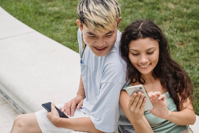 Happy couple stares at a cell phone.
