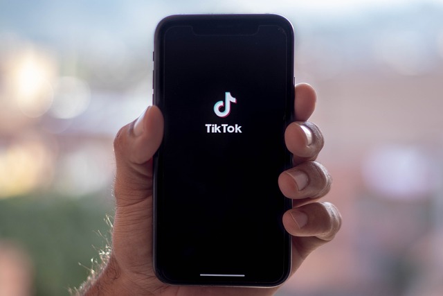 A person holds a smartphone displaying the TikTok logo.
