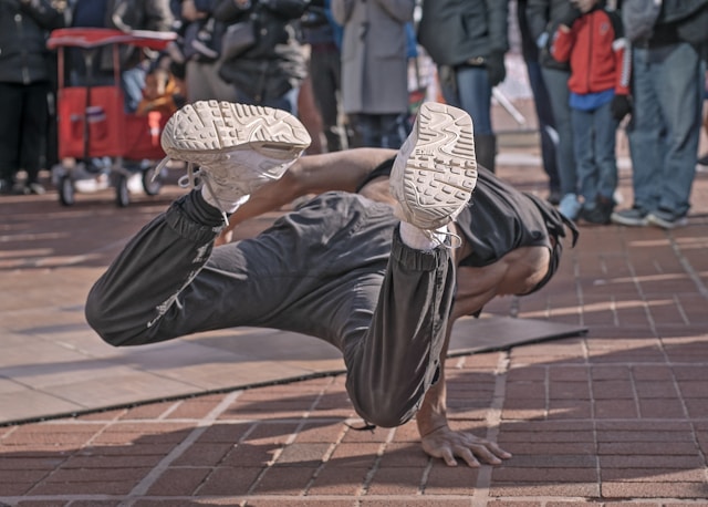 A man breakdances on the street. 
