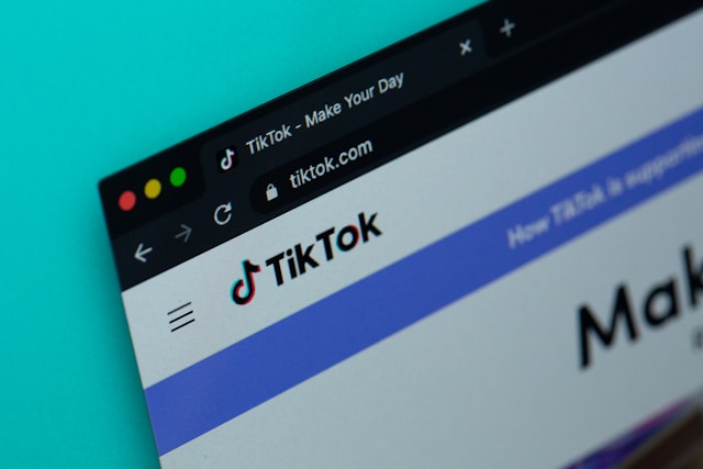 A laptop screen shows the TikTok For You feed and a login prompt. 
