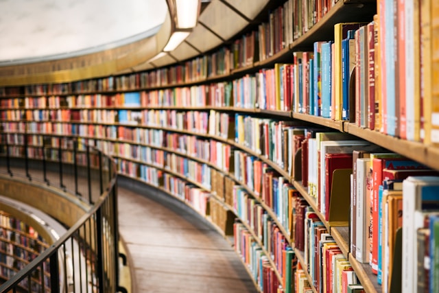 A long bookshelf full of books in a library. 
