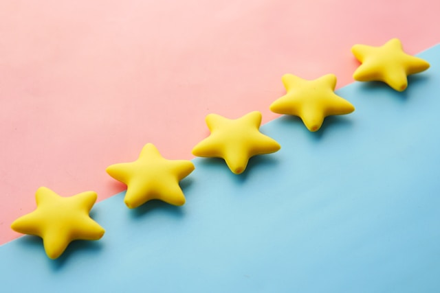 A row of five stars on a pink and blue surface. 
