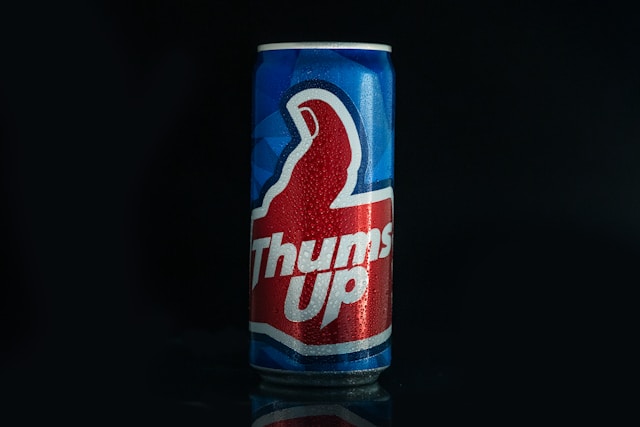 A blue soda can with a red thumbs-up image and the word “Thums up” printed in white. 
